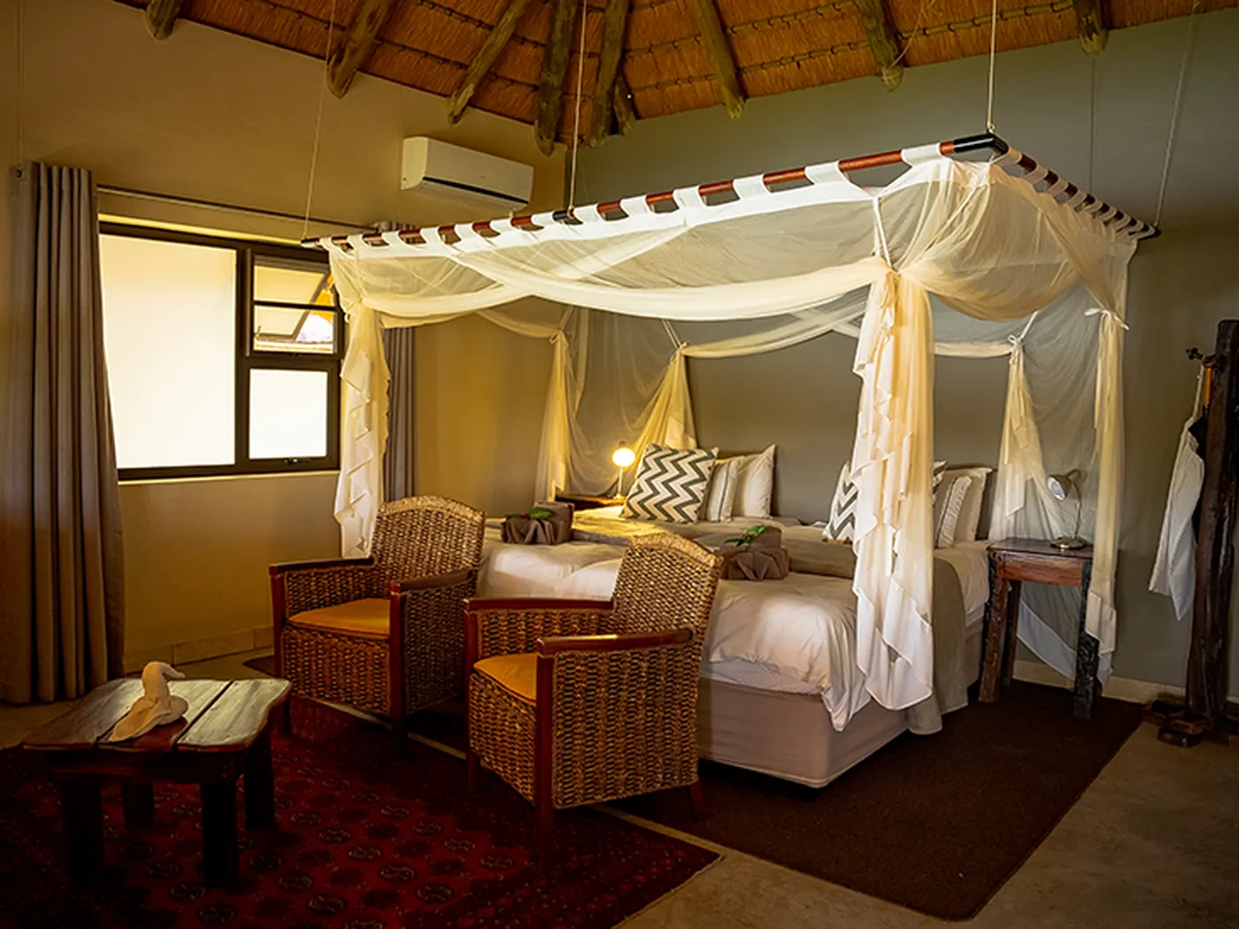 Interior of a thatched luxury chalet with a four-poster mosquito net